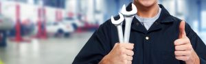 Mechanic holding wrenches and giving a thumbs-up.