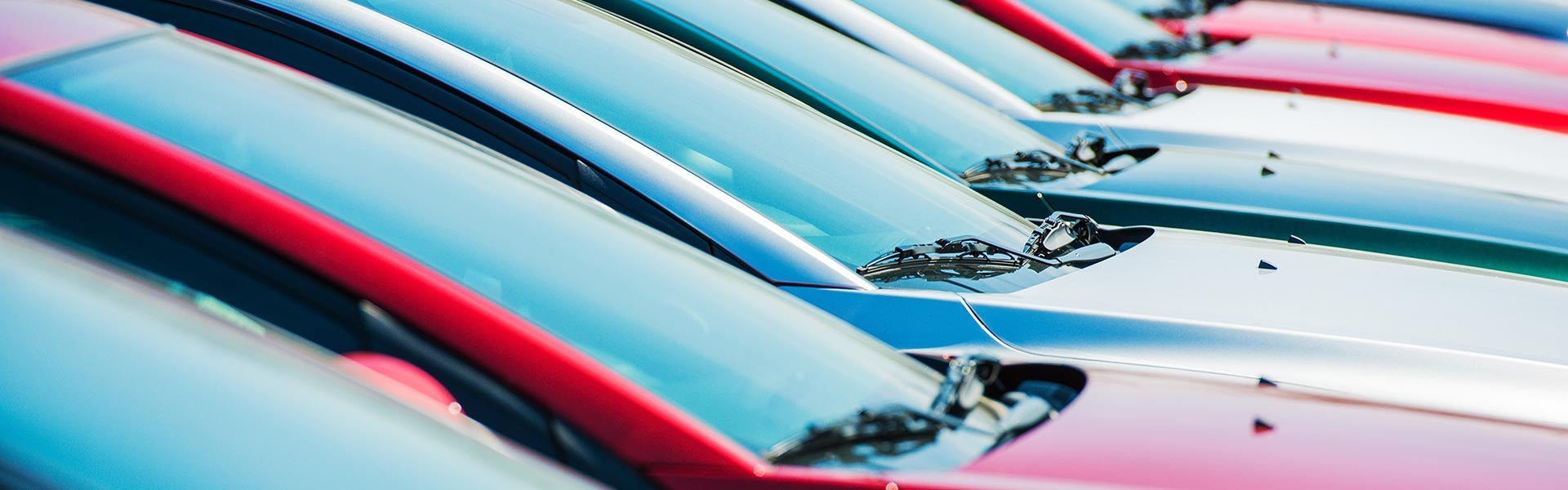 Row of colorful new cars parked in a dealership lot